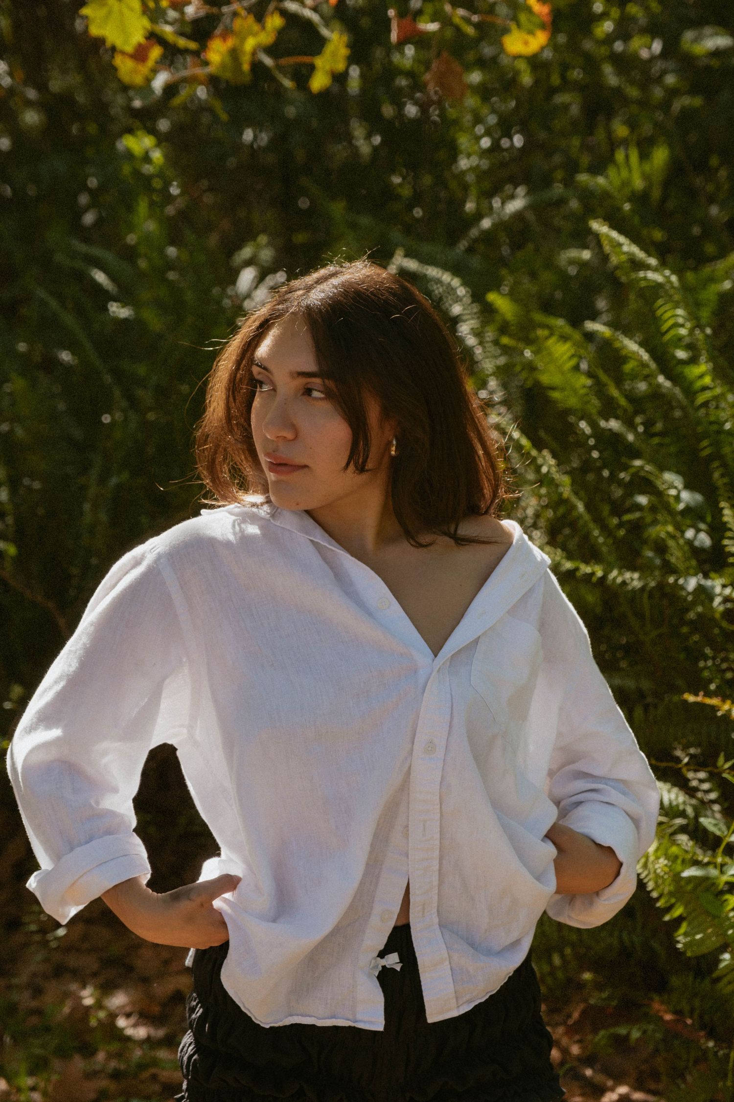 Dramatic poses in white button-down shirt captured in natural sunlit setting.