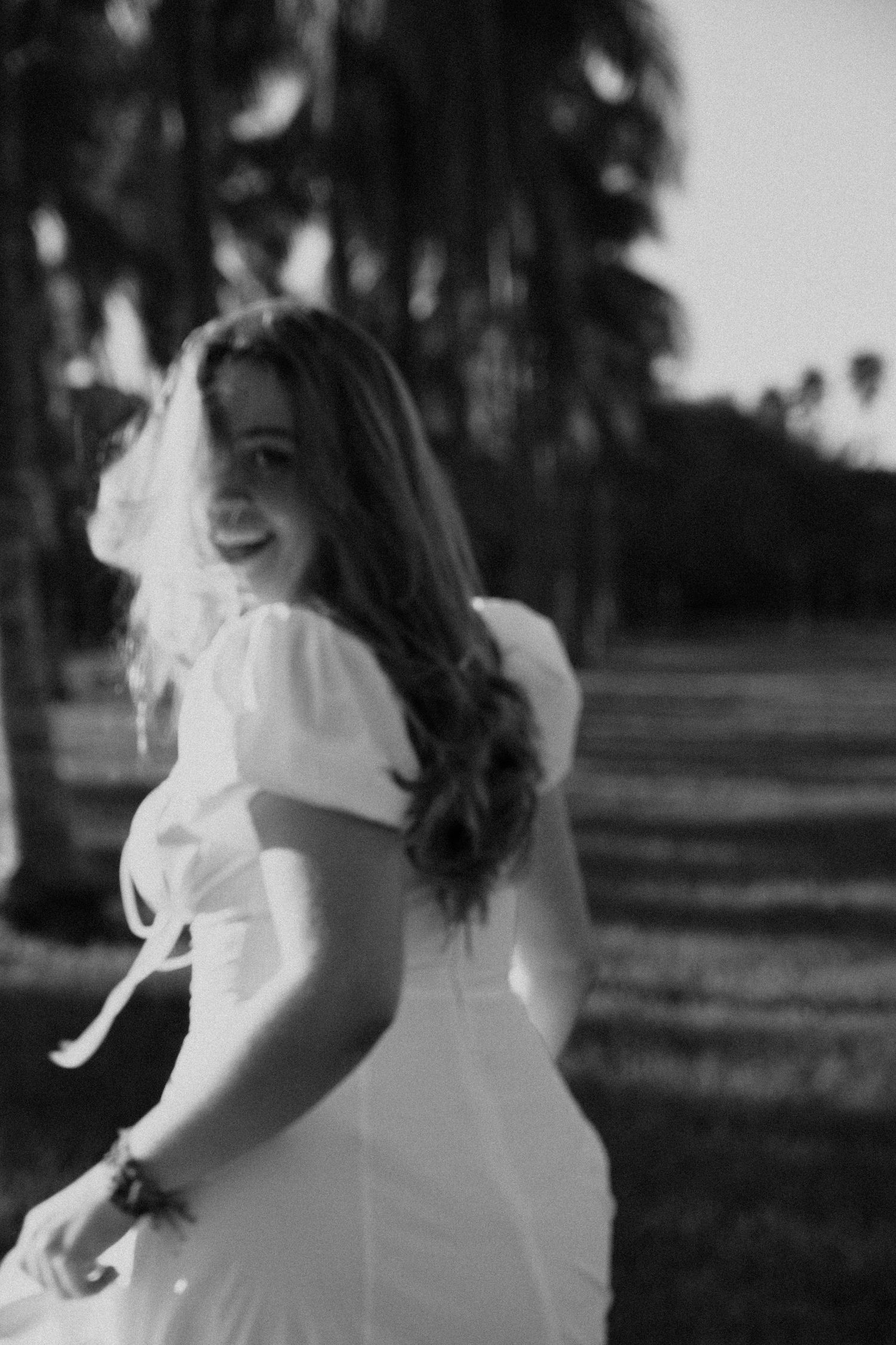 A person in a white dress twirls joyfully in a black and white outdoor setting.