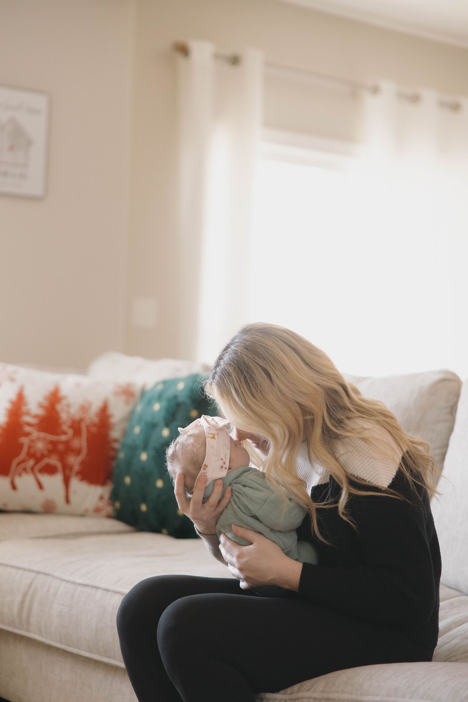 A person reclines on a couch with decorative holiday pillows in a bright, modern living room.