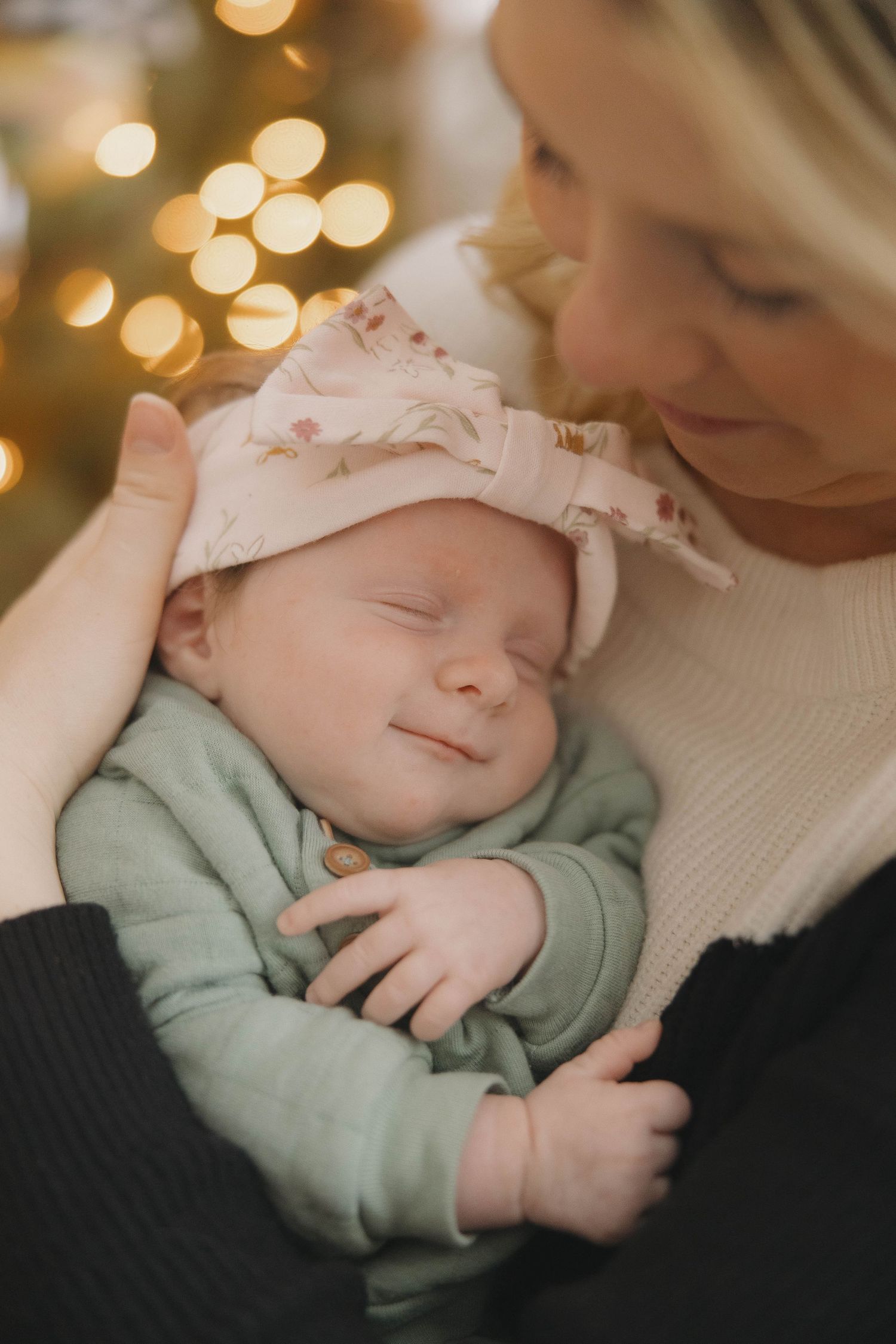 A sleeping baby in mint green clothing rests peacefully under warm glowing lights.