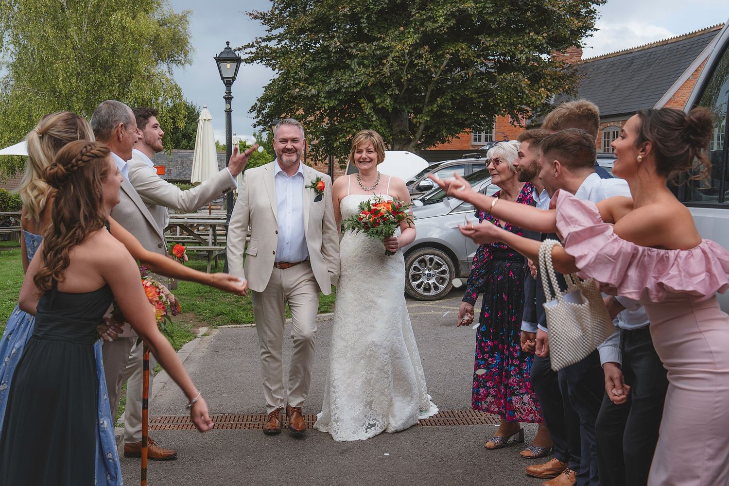 Wedding party enjoys dinner and conversation at a rustic wooden table during reception celebration.