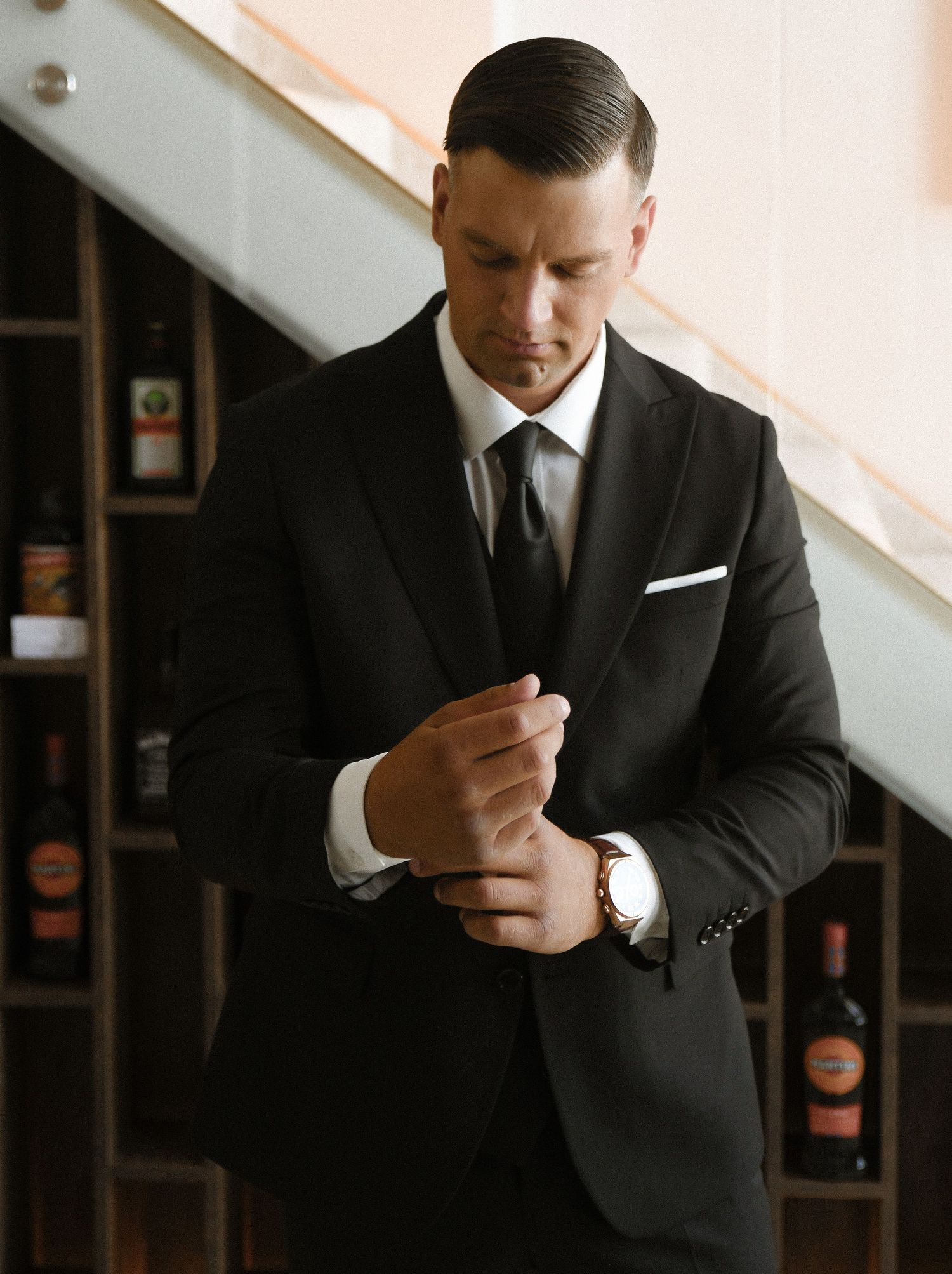 A close-up sequence of someone in a dark suit adjusting their tie and cufflinks.