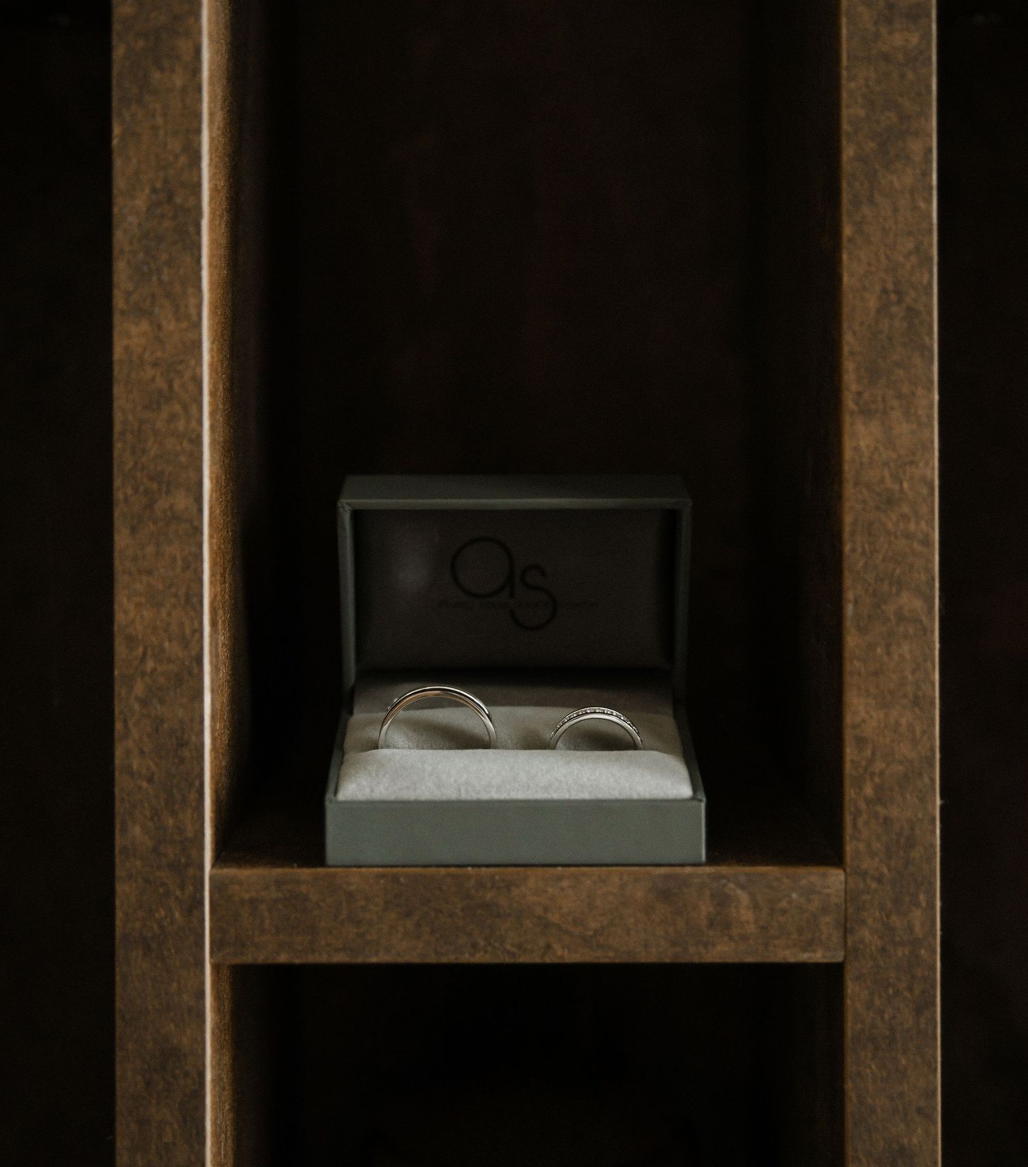 A wooden display shelf with glasses and boxes in shadow.
