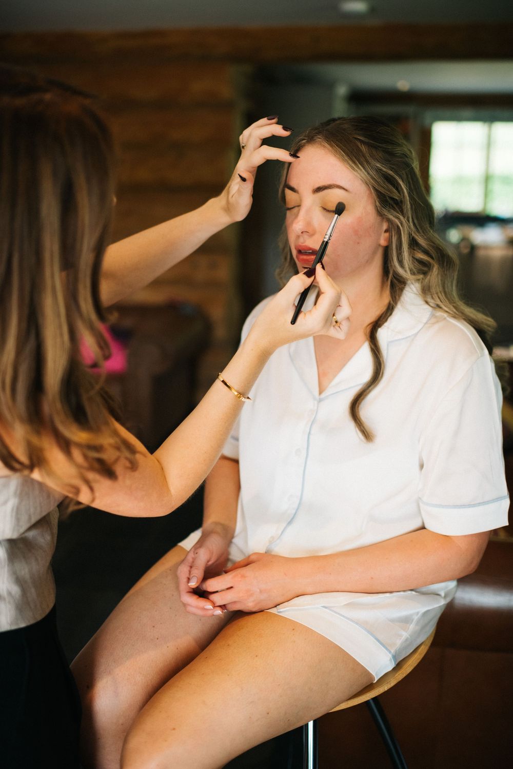 Woman in white getting ready for special event in rustic indoor setting.