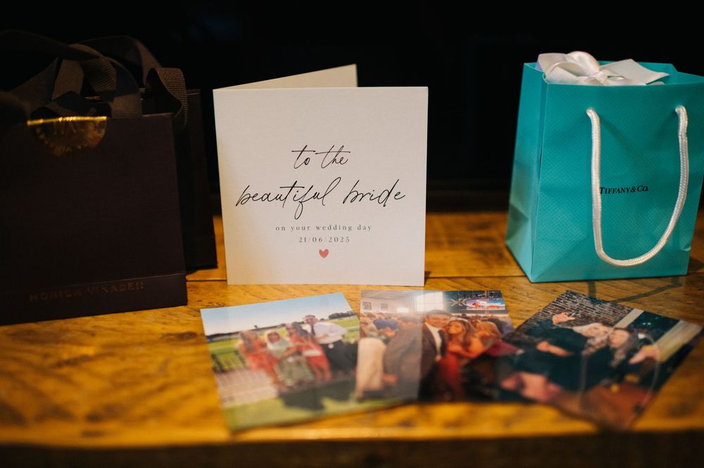 Wedding cards and gift bags displayed on wooden surface with photos.