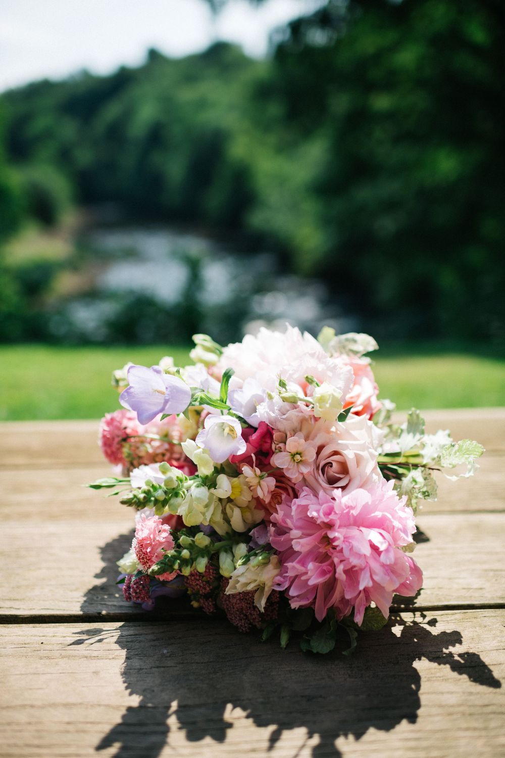 Pink and white floral crown with dahlias and delicate blooms laid on wooden surface.