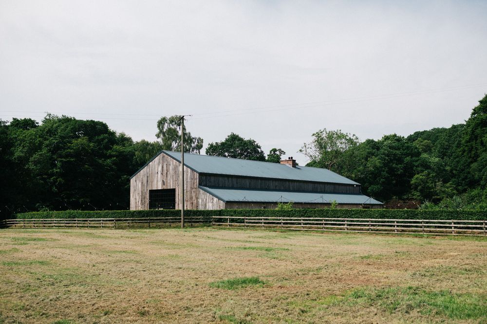 Rural farm landscape with green fields and agricultural buildings in the distance.