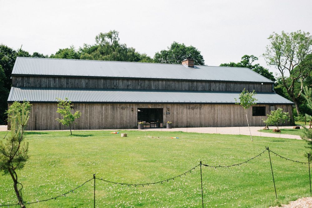 Long barn-style buildings on a green lawn surrounded by trees.