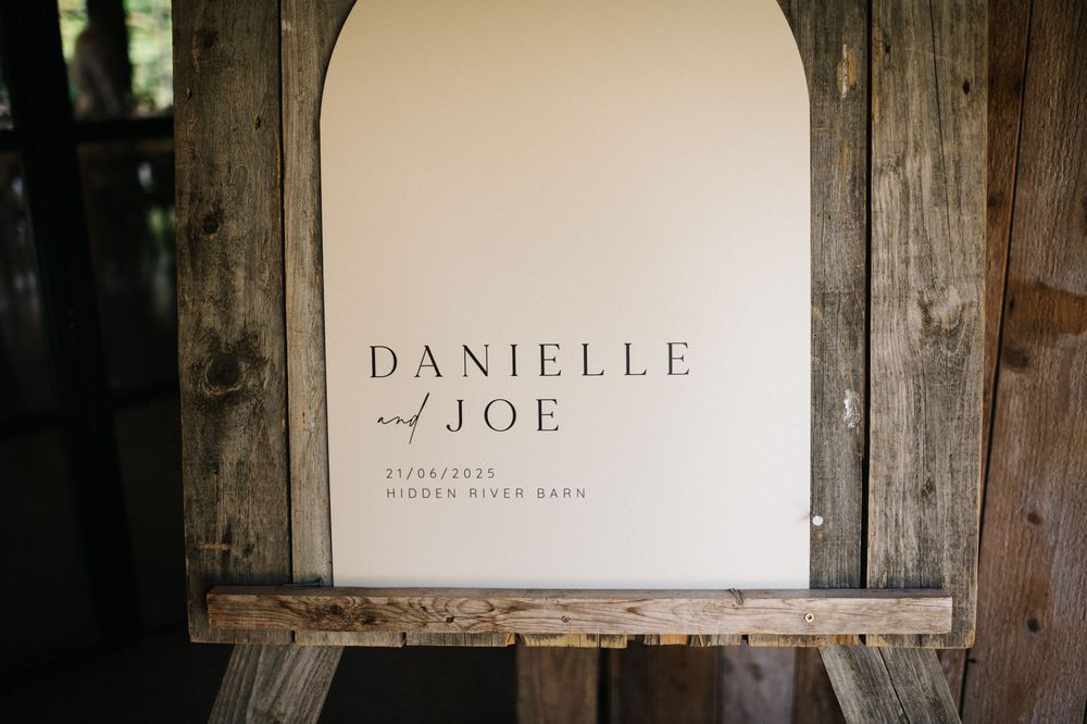 Rustic wooden wedding sign with couple's names in elegant typography.