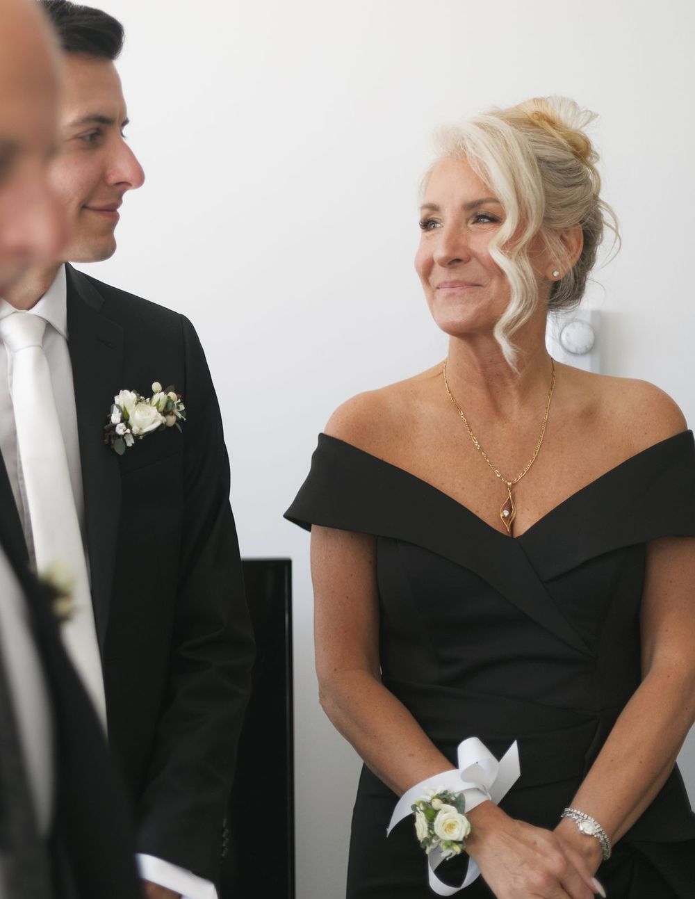 Elegant woman in black off-shoulder dress at wedding ceremony.