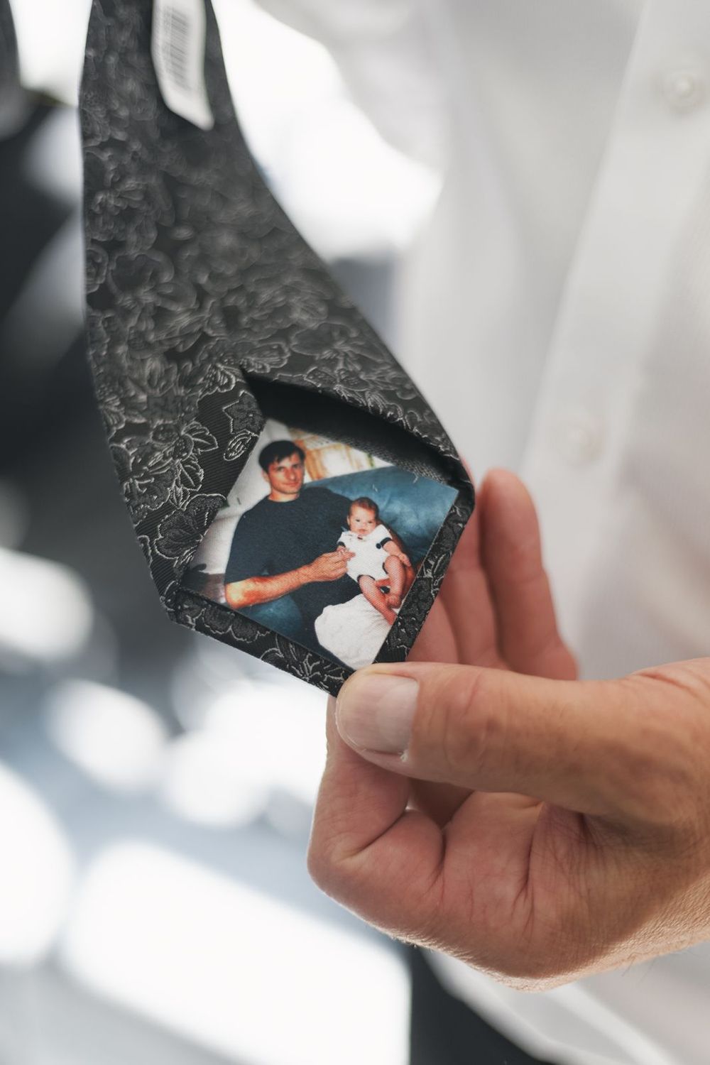 Hand holding tie with small family photo tucked inside.