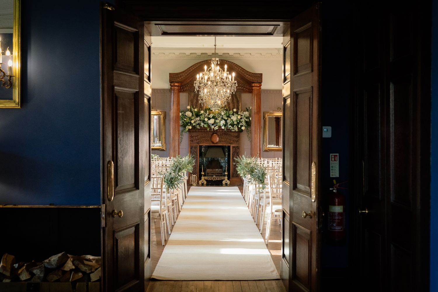 Long corridor with crystal chandeliers and elegant white trim in a grand estate. Ellingham Hall