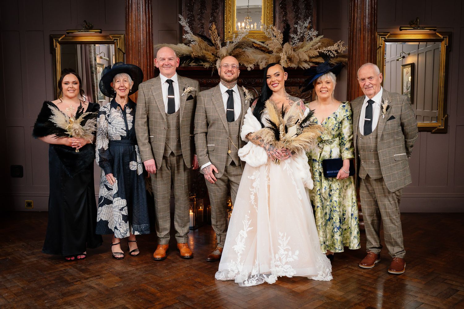 Wedding party poses in formal attire inside an elegant historic venue with classic architecture. Ellingham Hall