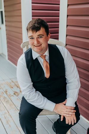 Portrait session showing formal attire against a red wall backdrop.