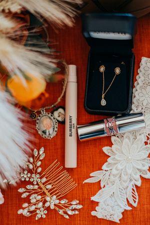 Wedding accessories including delicate white floral hair combs, jewelry box, and bridal decorations on orange surface.