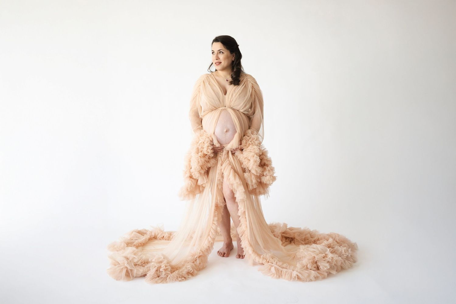 Elegant maternity portraits with champagne-colored tulle dresses in studio setting.