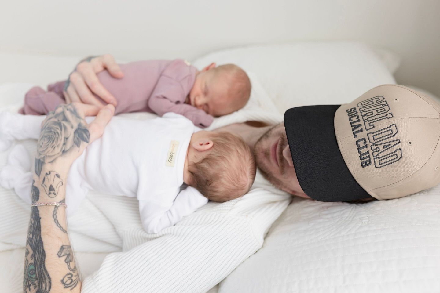 A sleeping baby wearing white clothing lies peacefully on a bed with white linens.