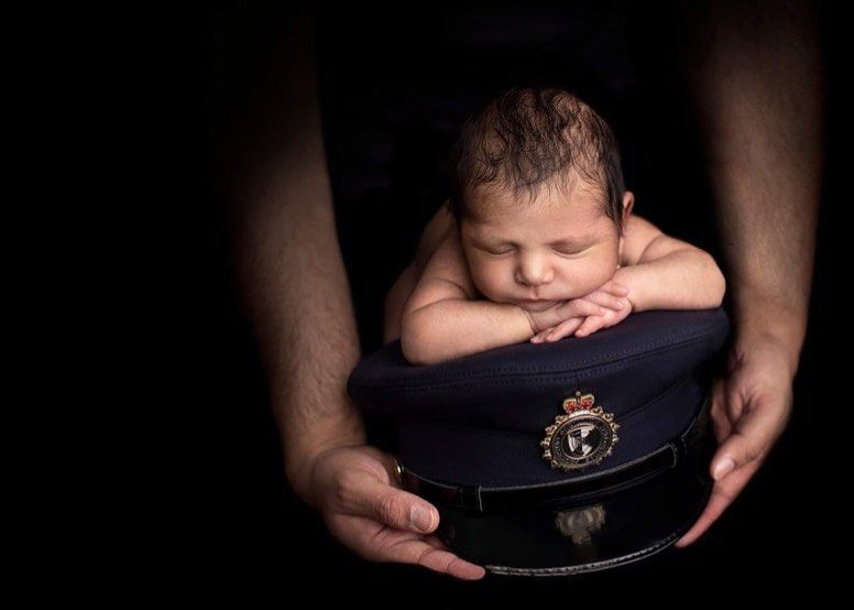 A series of dark, moody photos showing hands holding and presenting a navy blue military-style cap against a black background.