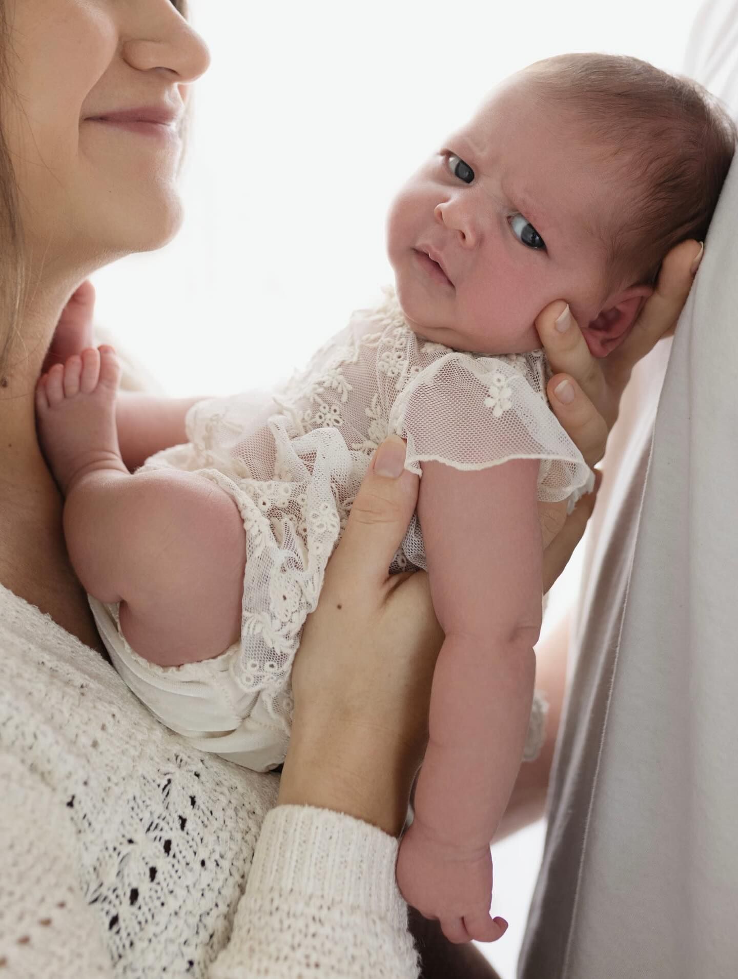 A tender moment of nurturing and bonding between parent and infant in soft white lighting.