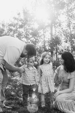 Candid family photoshoot in a sunlit orchard showing joyful interactions and laughter.
