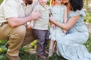 Candid moments of a family spending time together outdoors among fruit trees.