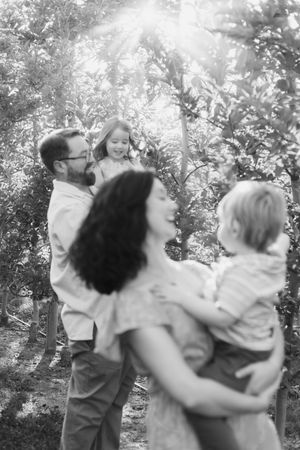 A joyful family moment captured in black and white among fruit trees.