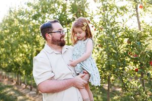 Candid family photos showing joyful interactions between loved ones in a sunlit orchard setting.
