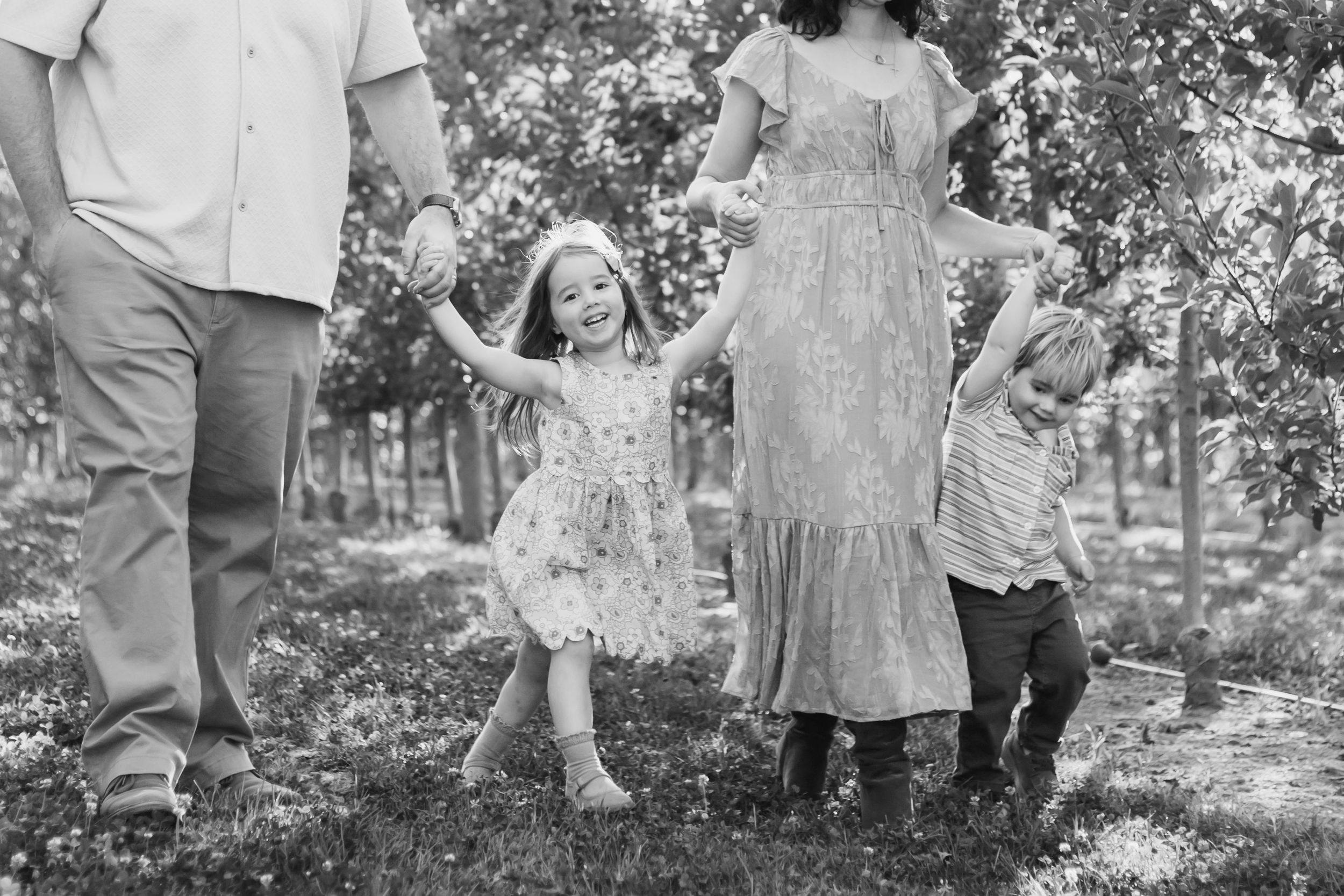 A black and white photo series of people playing and throwing leaves in an outdoor garden setting.
