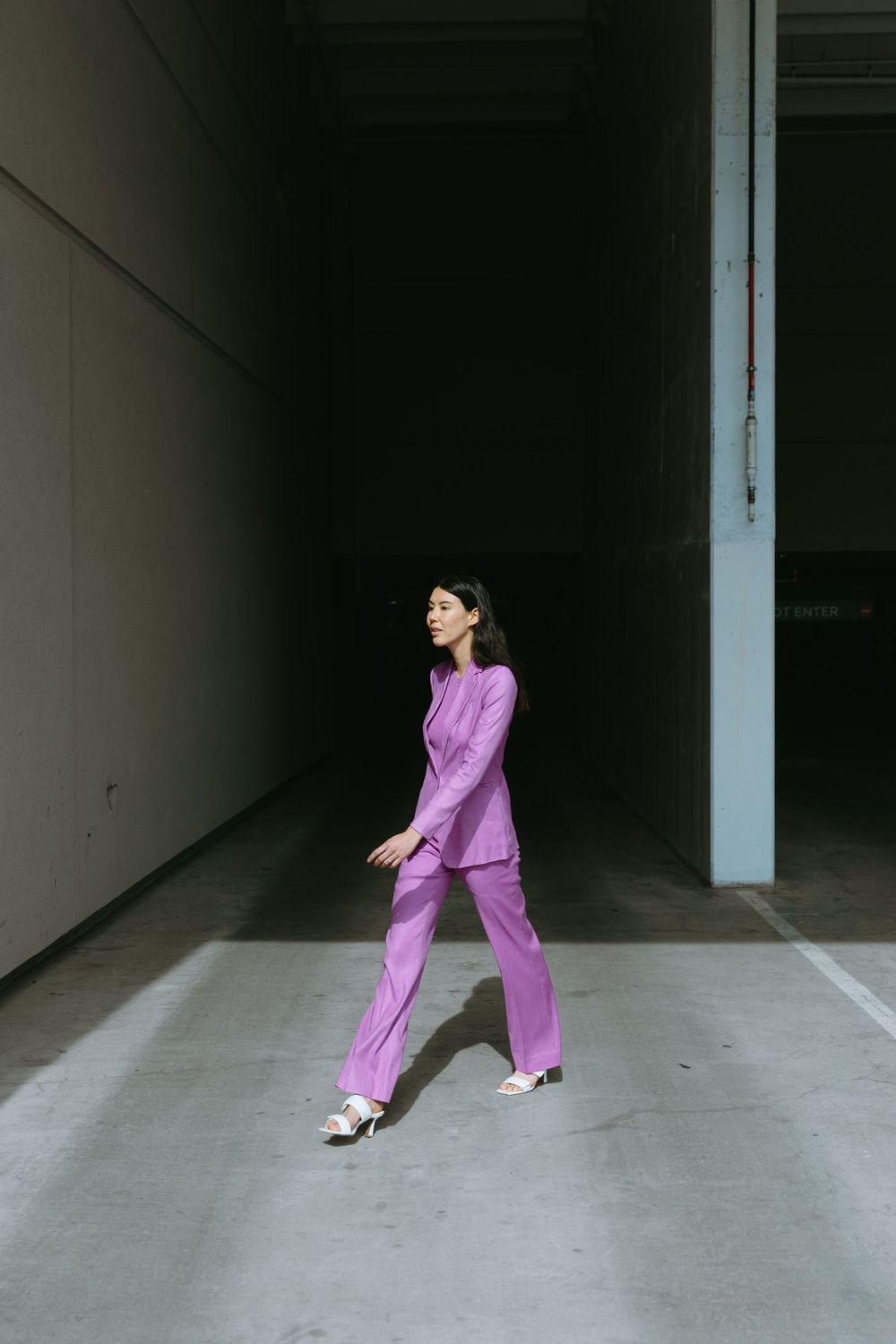 Figure in purple outfit moving dynamically through minimalist concrete space.