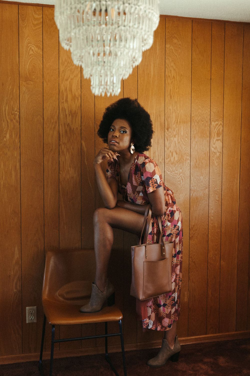 Vintage-style photoshoot in wood-paneled room with crystal chandelier and retro furniture.