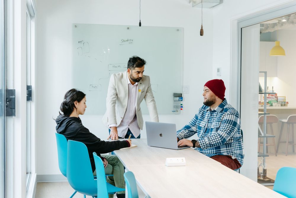 Modern office space with glass walls and people having a casual meeting.