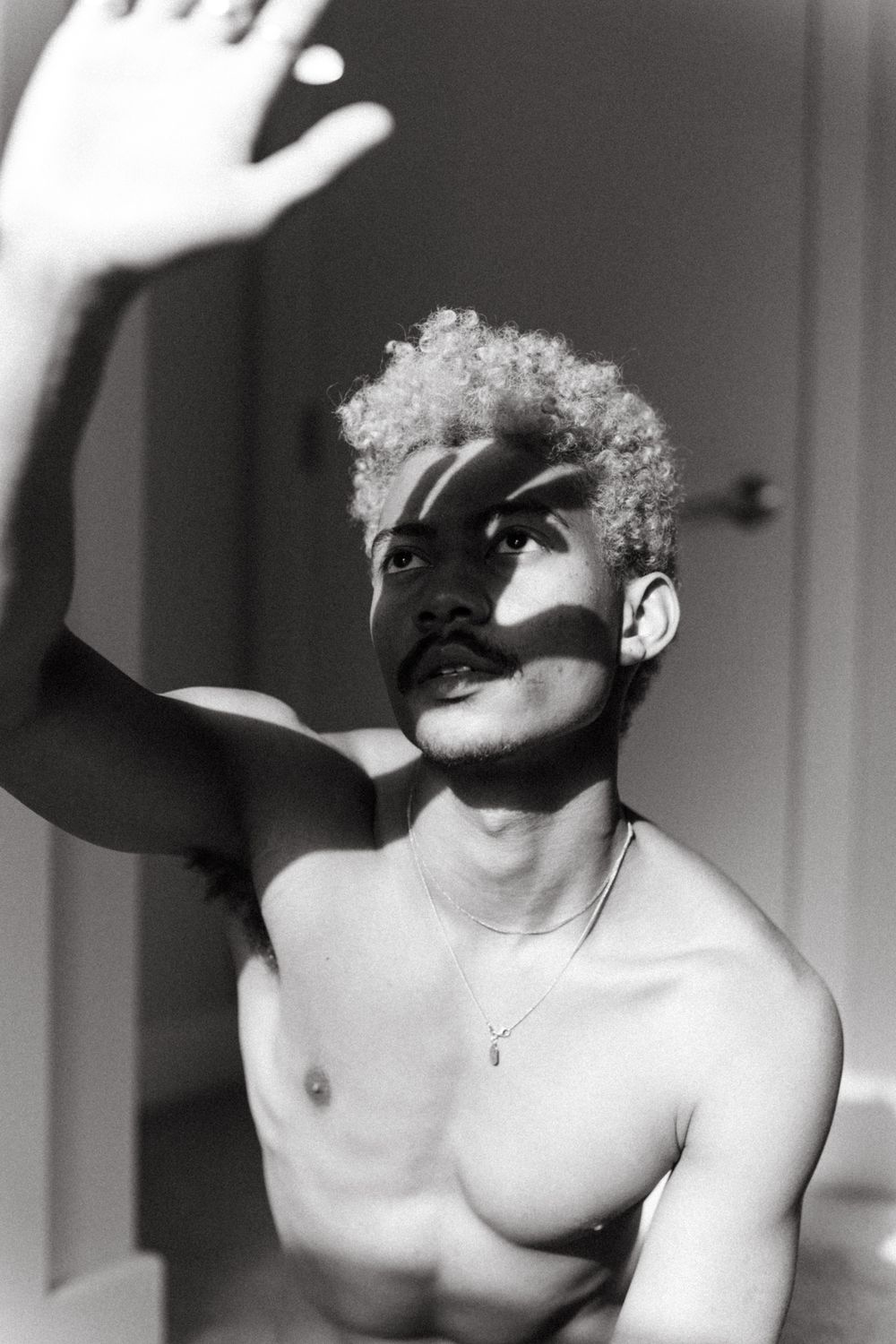 Artistic black and white portrait series with dramatic shadows and raised hands.