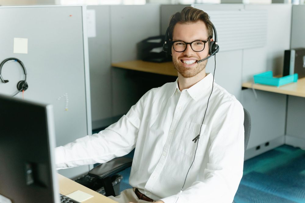 Customer service team members wearing headsets while working at bright modern office workstations.