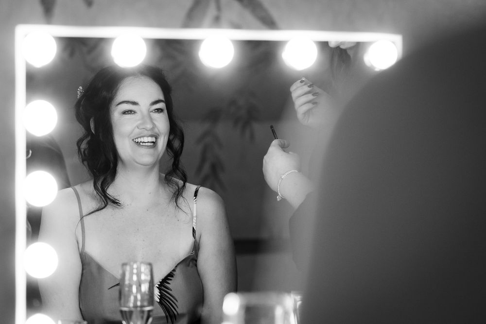 Candid black and white getting ready moments with bridesmaids in a dressing room.