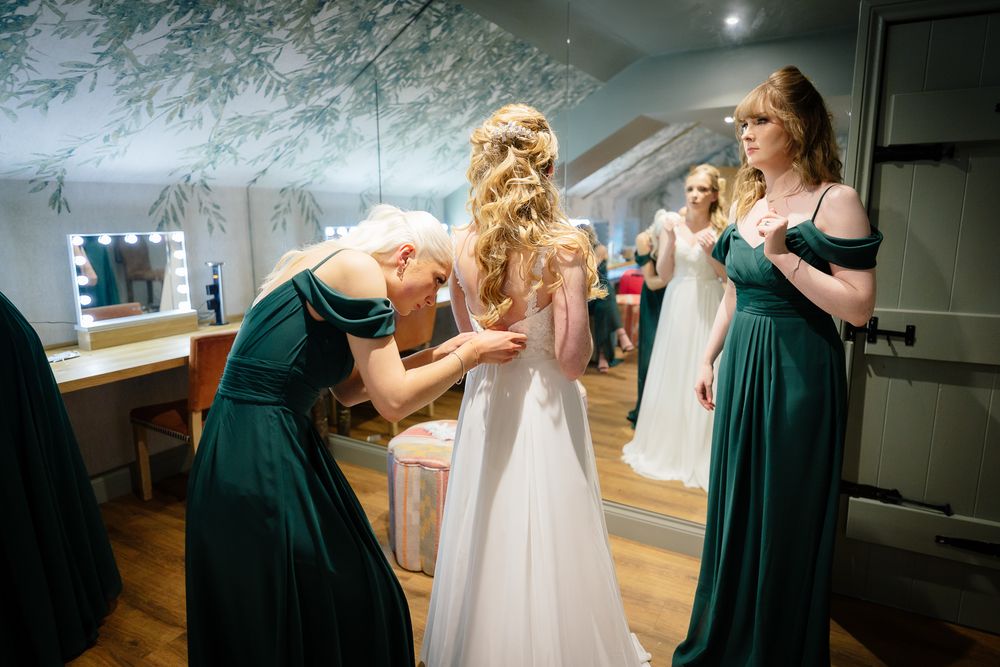 Wedding preparation scene showing emerald green bridesmaid dresses and white bridal gown.