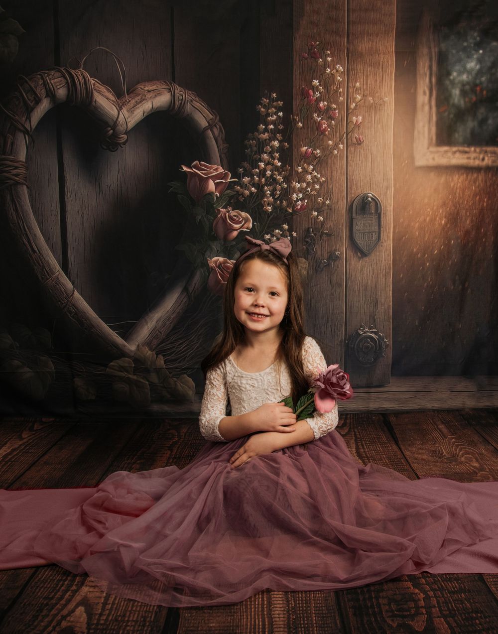 Whimsical photo of someone in a mauve tulle dress sitting by a rustic door with a heart decoration.