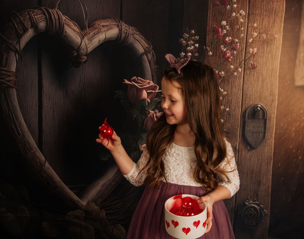 Romantic portrait with heart decor showing someone in a dress holding a valentine themed container.