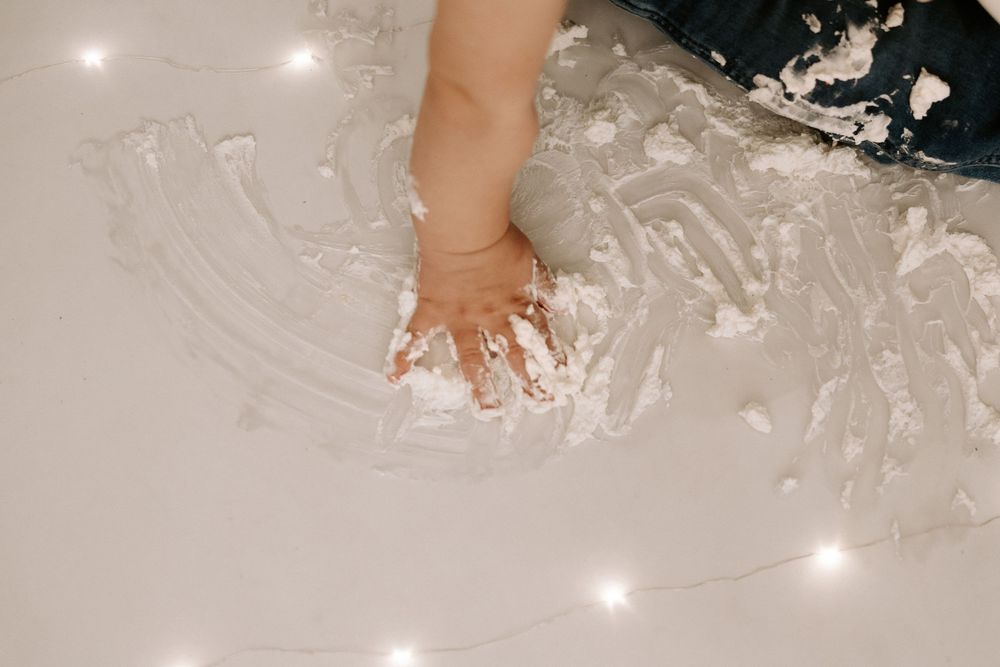Small feet step into a pile of white flour or powdery substance on a light surface creating a messy baking scene.