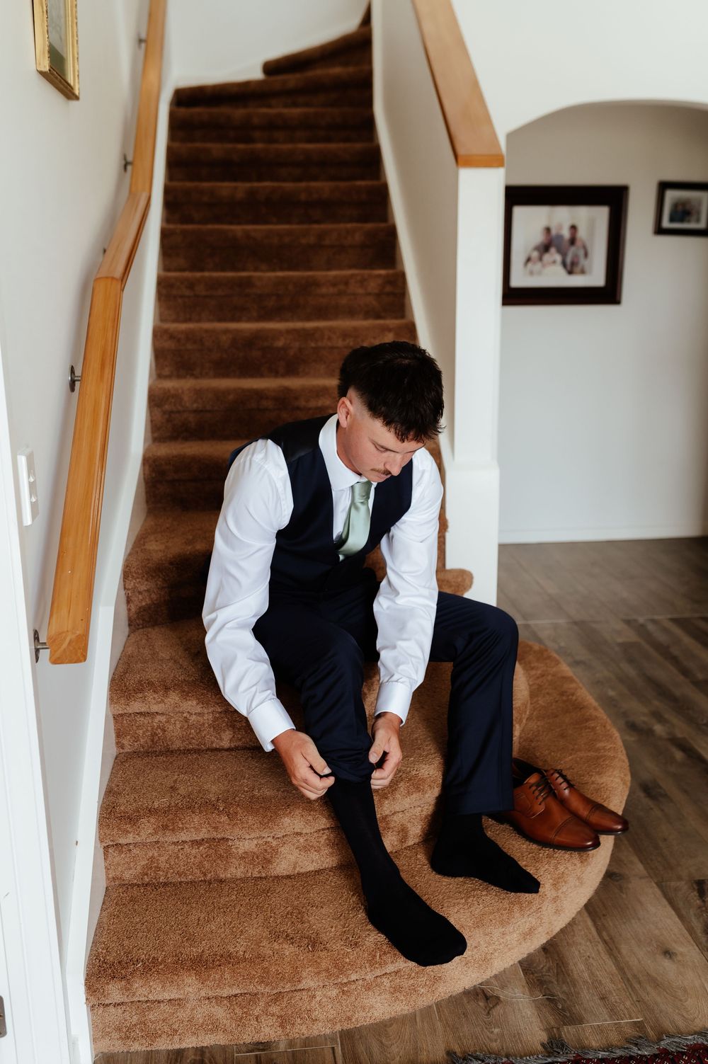 Wedding preparations showing formal shoes and attire being put on while seated on carpeted stairs.
