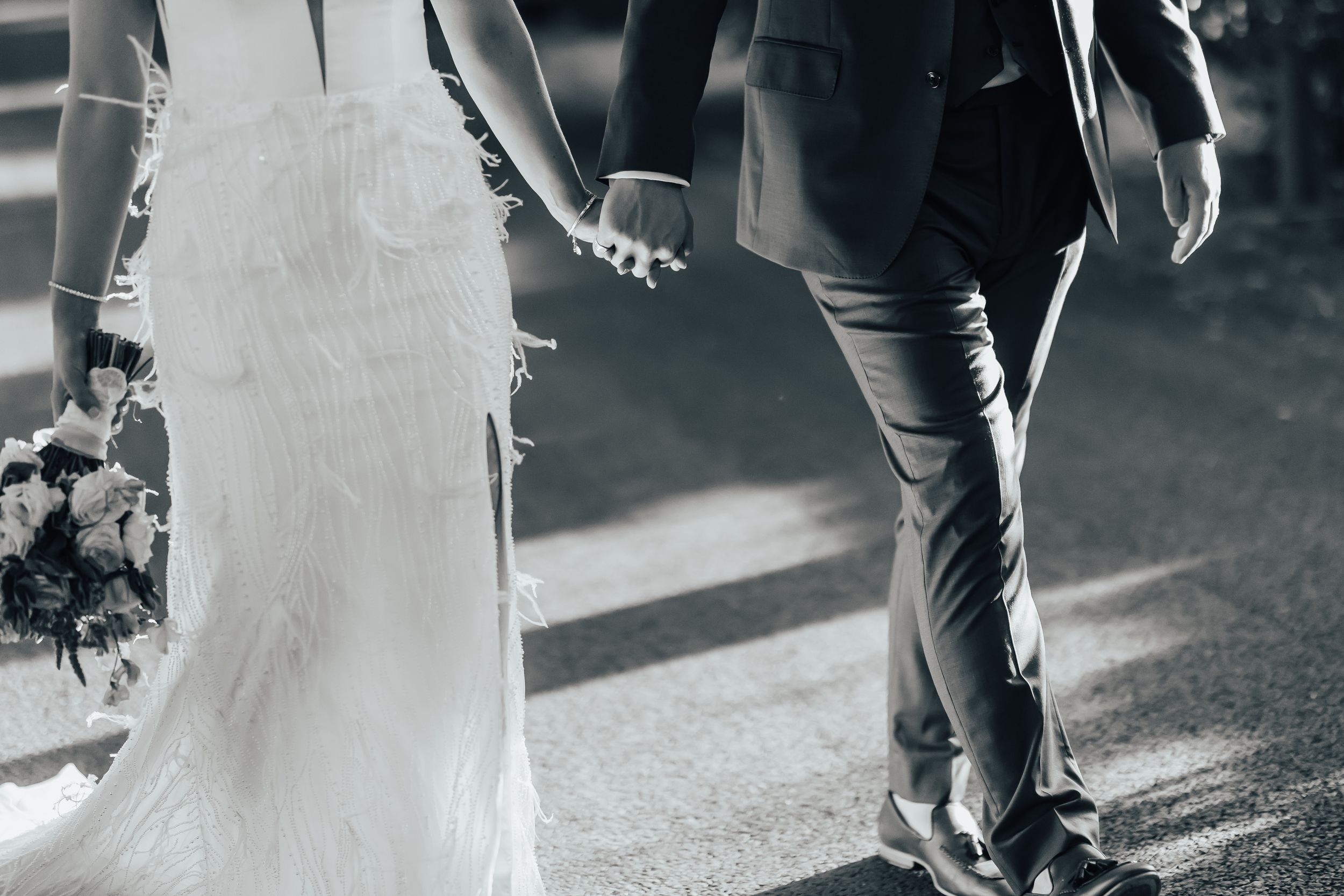 A bride and groom hold hands during their wedding ceremony as they walk down a path together at Middleton Lodge, North Yorkshire.