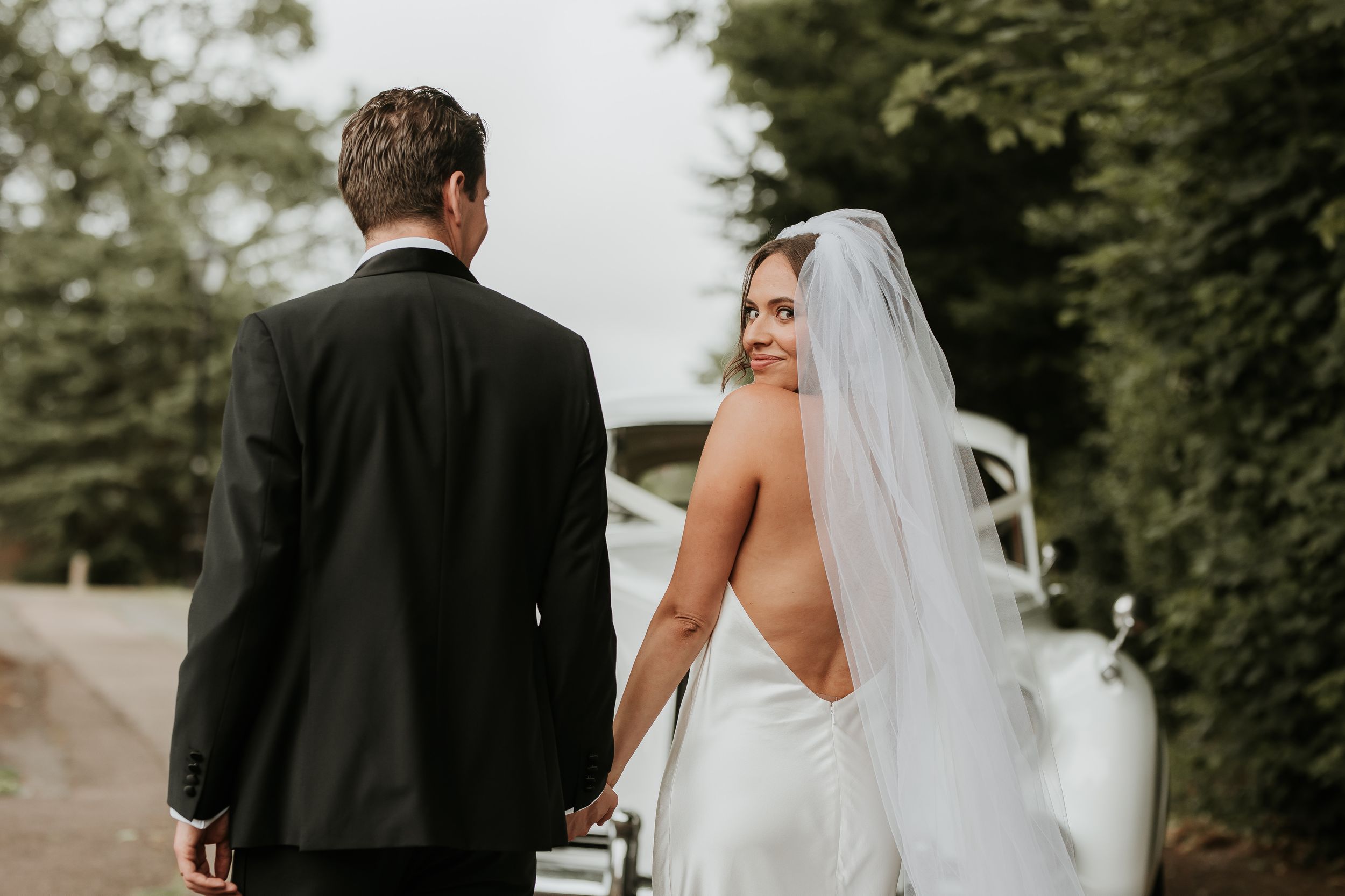A wedding couple stands together in a lush green garden setting during their romantic outdoor ceremony.