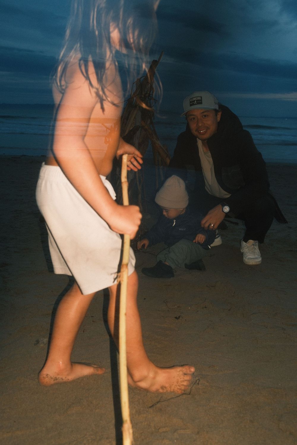 A sequence of photos showing someone digging a hole in the sand at night on a beach with a wooden stick.