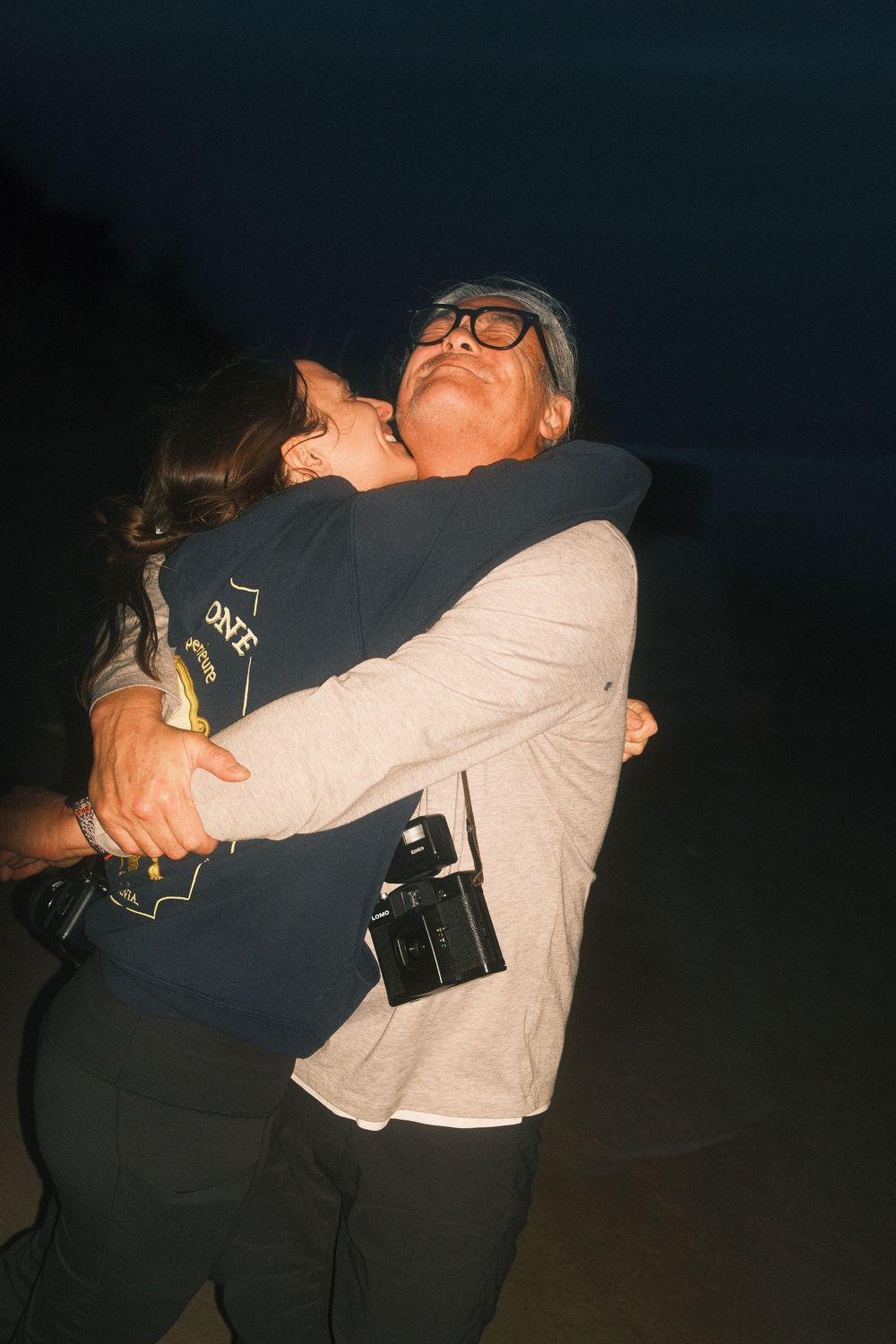 Two people embrace in a playful sequence of candid dance moves against a dark background.