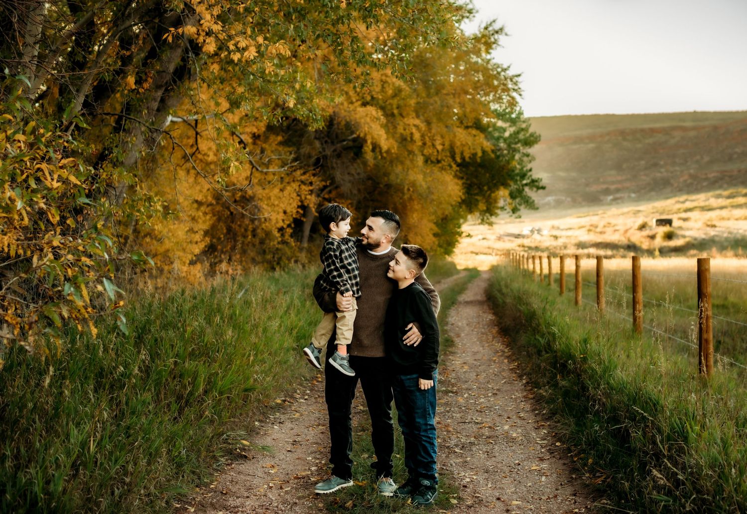 A couple shares a tender moment on a scenic autumn trail surrounded by golden foliage and rolling hills.