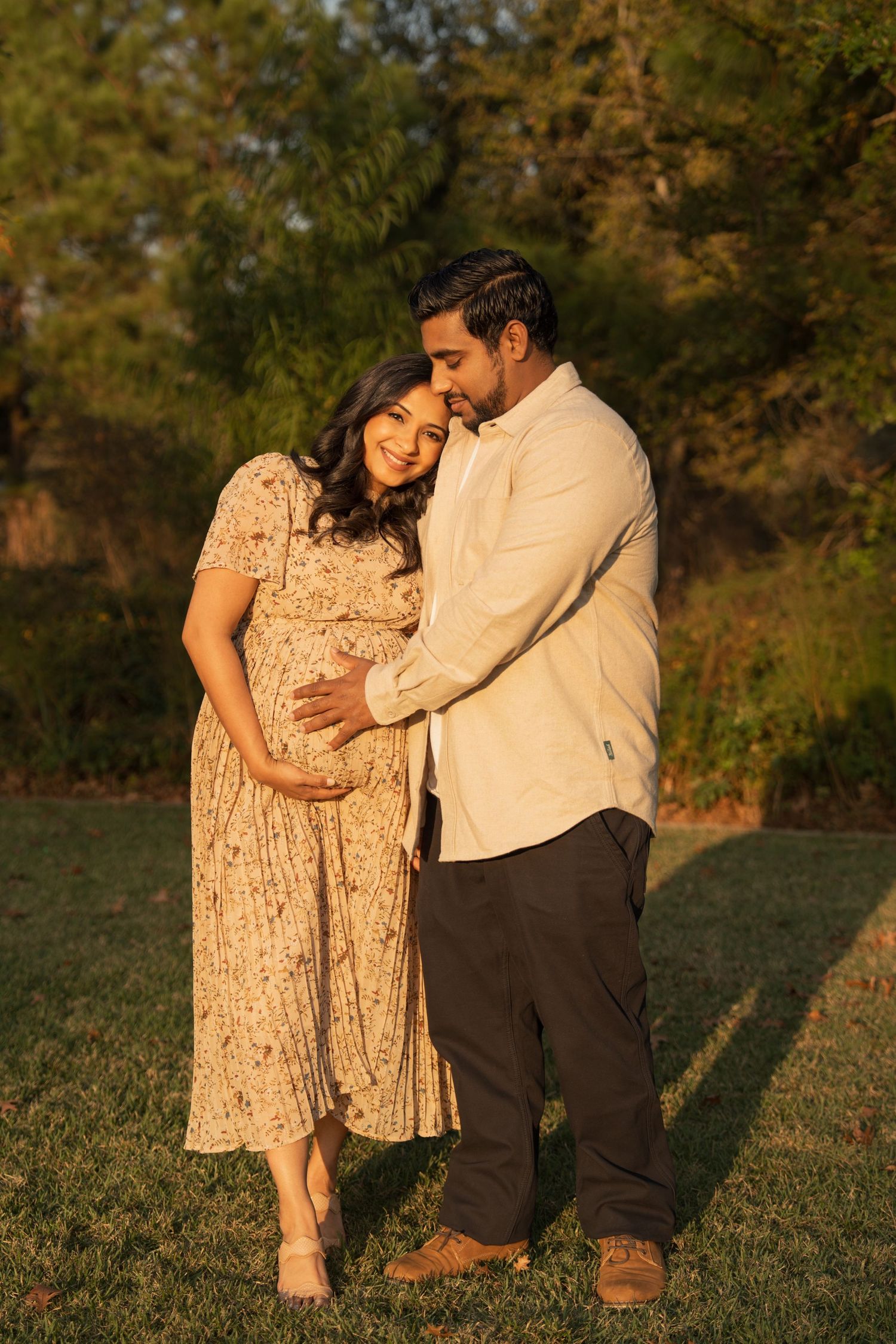 A romantic outdoor portrait of a couple in warm evening light wearing elegant attire.