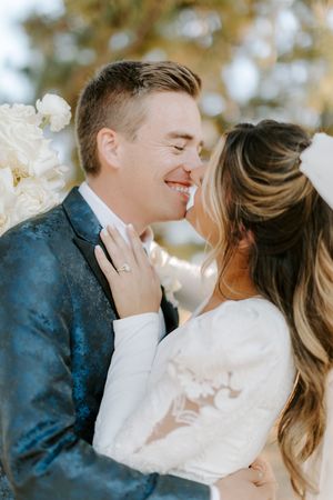 Romantic couple sharing tender kisses in a dreamy outdoor setting with soft natural lighting and blooming flowers.