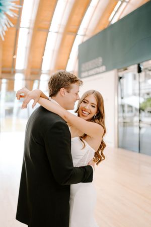Romantic wedding couple shares intimate dance moments in a light-filled venue with wooden beams.