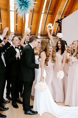 Wedding party celebrates with joyful dancing in a modern venue with blue decor accents.