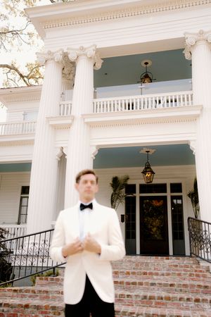 Classic Southern mansion exterior features grand white columns and a two-story porch with ornate architectural details.