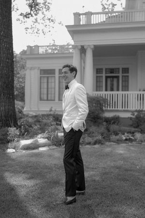 A black and white photo series showing a person in formal attire standing on a lawn in front of a stately house.
